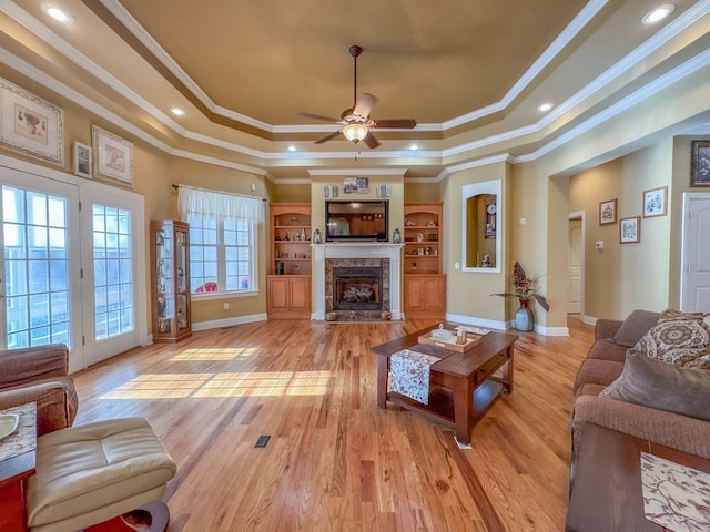 living room with a fireplace, a raised ceiling, and light wood-type flooring