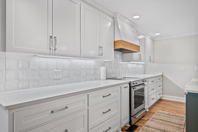 kitchen featuring light hardwood / wood-style floors, decorative backsplash, electric range, white cabinetry, and custom range hood