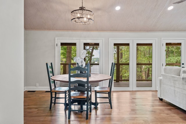 dining space featuring hardwood / wood-style flooring, crown molding, french doors, and an inviting chandelier