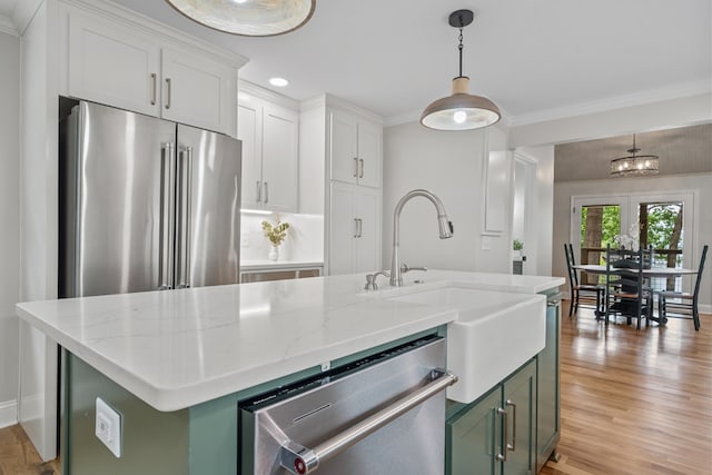 kitchen with white cabinetry, appliances with stainless steel finishes, a kitchen island with sink, and green cabinets