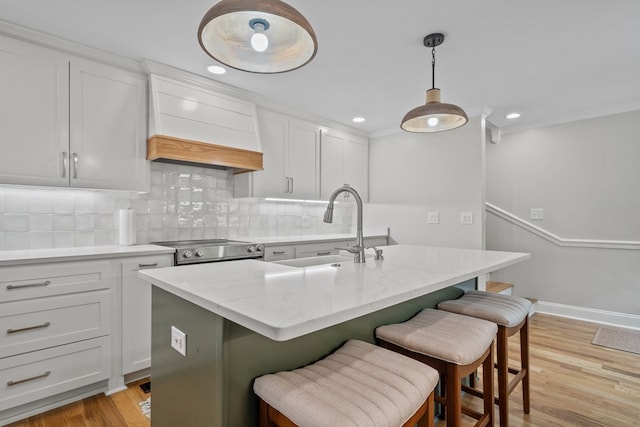 kitchen with tasteful backsplash, a center island with sink, sink, stainless steel electric range oven, and custom range hood