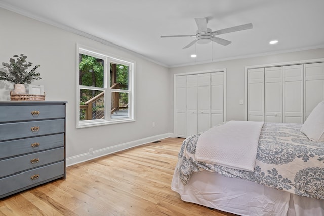 bedroom featuring ceiling fan, light hardwood / wood-style flooring, crown molding, and multiple closets