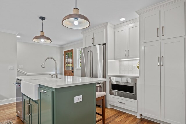 kitchen featuring white cabinetry, stainless steel appliances, a kitchen breakfast bar, a kitchen island, and pendant lighting