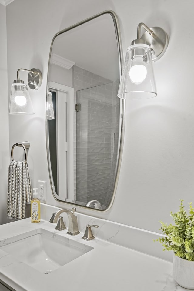 bathroom with a shower with shower door, vanity, and crown molding