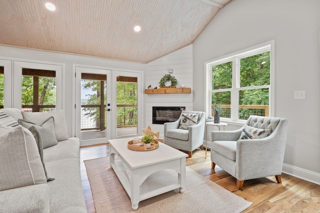 living room with wooden ceiling, a large fireplace, a healthy amount of sunlight, and vaulted ceiling