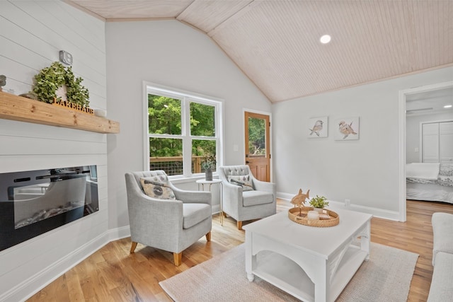 living room with light wood-type flooring, wooden ceiling, a large fireplace, and vaulted ceiling