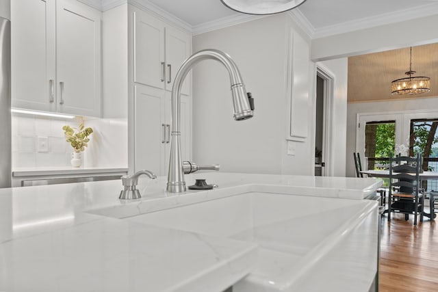 interior space featuring backsplash, hardwood / wood-style floors, sink, ornamental molding, and a chandelier