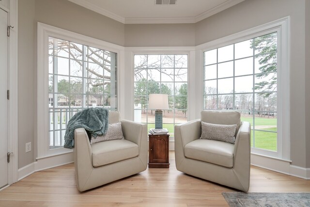 living area featuring light wood-type flooring and ornamental molding