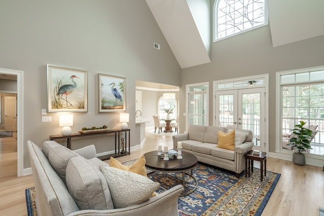 living room featuring light hardwood / wood-style floors, a high ceiling, and french doors