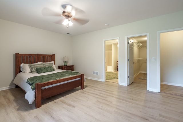 bedroom with a walk in closet, a closet, ceiling fan, and light hardwood / wood-style floors