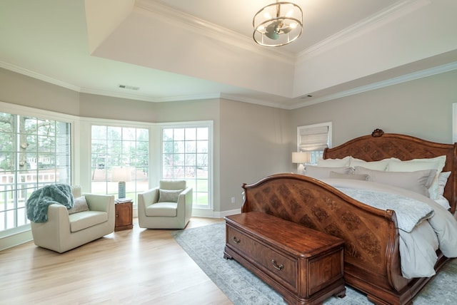 bedroom featuring light wood-type flooring, a tray ceiling, an inviting chandelier, and ornamental molding