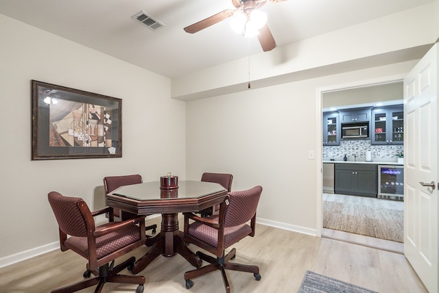 dining area with wine cooler, ceiling fan, and light hardwood / wood-style floors