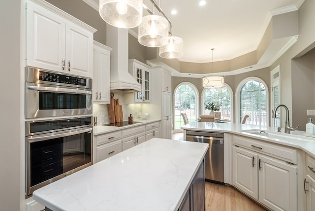 kitchen with a center island with sink, sink, hanging light fixtures, white cabinetry, and stainless steel appliances