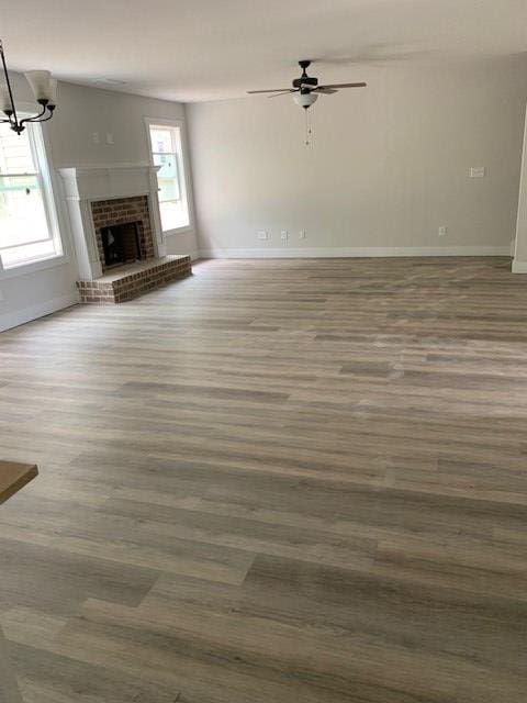 461 Riley Cir, Milledgeville, GA 31061 - unfurnished living room featuring ceiling fan, wood finished floors, a brick fireplace, and a chandelier