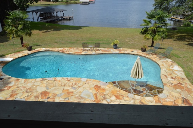 view of swimming pool with a lawn, a patio area, and a water view