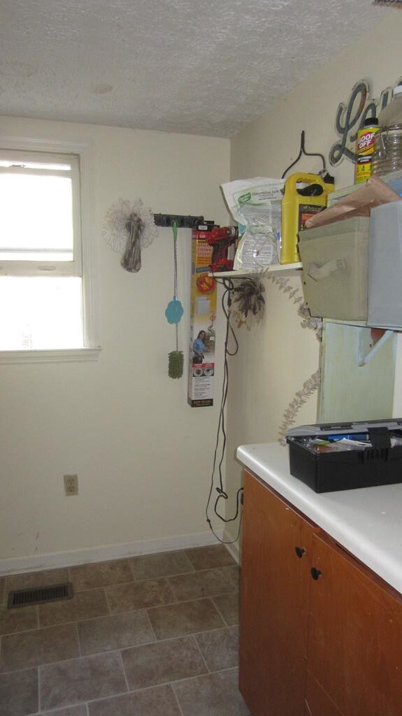 131 NE Carriage Ct, Milledgeville, GA 31061 - clothes washing area featuring a textured ceiling, baseboards, and visible vents
