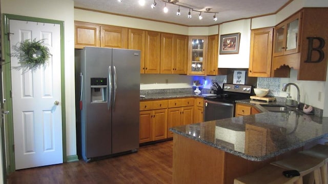 131 NE Carriage Ct, Milledgeville, GA 31061 - kitchen with a sink, a peninsula, brown cabinets, dark stone counters, and stainless steel appliances