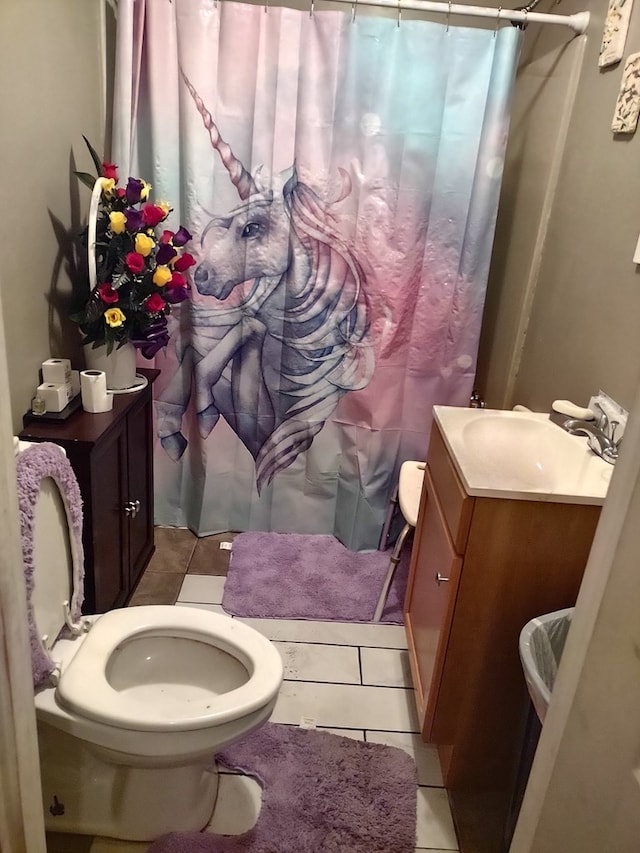 bathroom with tile patterned floors, vanity, toilet, and curtained shower