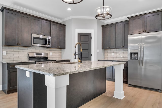 kitchen with sink, light stone countertops, stainless steel appliances, and an island with sink