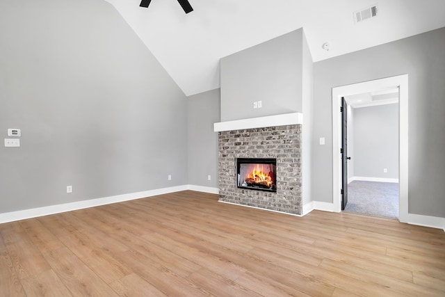 unfurnished living room featuring ceiling fan, light hardwood / wood-style flooring, high vaulted ceiling, and a brick fireplace