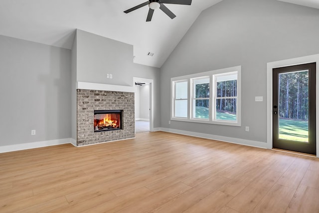 unfurnished living room featuring light wood-type flooring, high vaulted ceiling, a brick fireplace, and ceiling fan