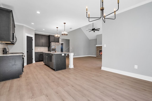 kitchen with a center island with sink, a stone fireplace, backsplash, and appliances with stainless steel finishes