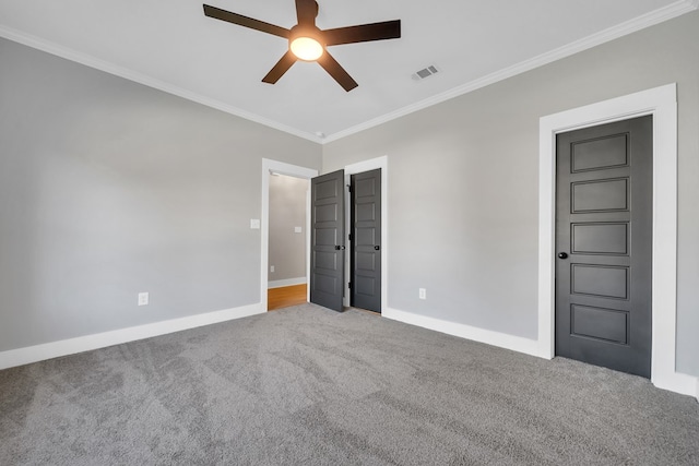 unfurnished bedroom featuring ceiling fan, crown molding, and carpet floors