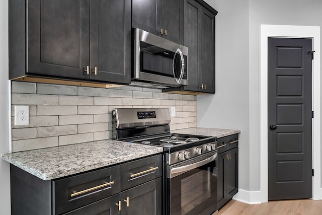 kitchen featuring light stone countertops, appliances with stainless steel finishes, light wood-type flooring, and decorative backsplash