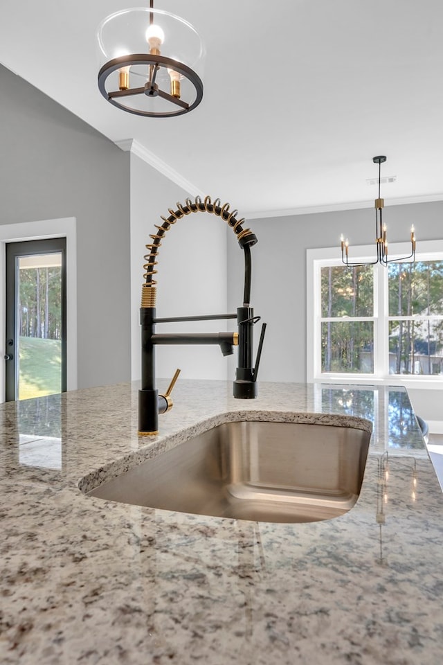 room details with light stone counters, sink, pendant lighting, and an inviting chandelier