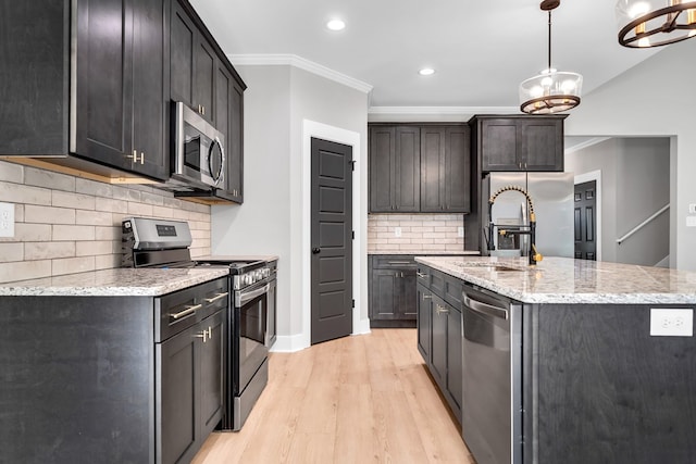 kitchen featuring a center island with sink, crown molding, decorative backsplash, light hardwood / wood-style floors, and stainless steel appliances