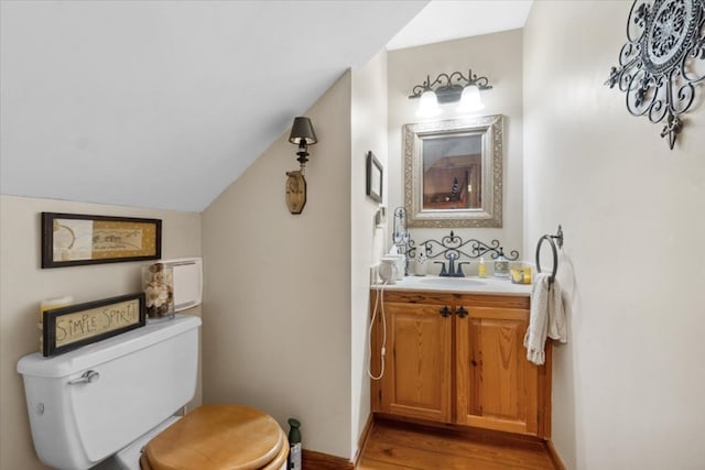 half bath featuring toilet, vanity, lofted ceiling, and wood finished floors