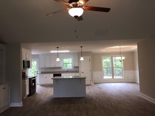 kitchen with a kitchen island, wainscoting, plenty of natural light, white cabinets, and black appliances