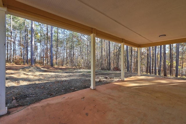 view of patio / terrace featuring a wooded view and a carport
