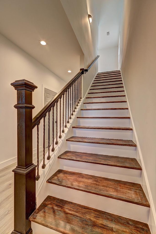 stairway with recessed lighting and wood finished floors