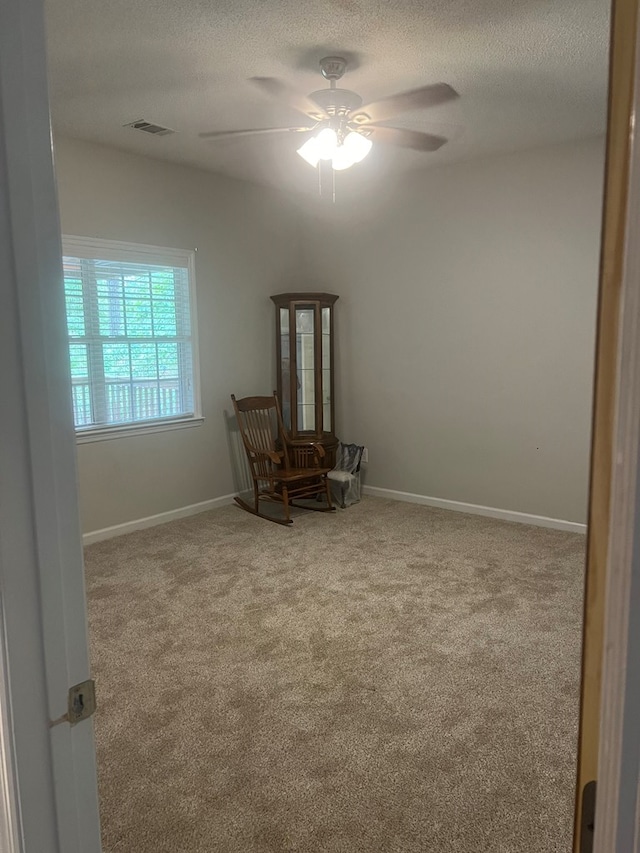 carpeted spare room with ceiling fan and a textured ceiling