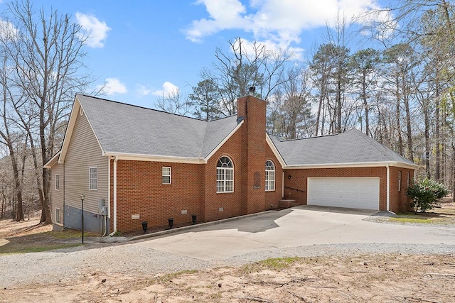 view of property exterior featuring a garage, brick siding, a chimney, and driveway