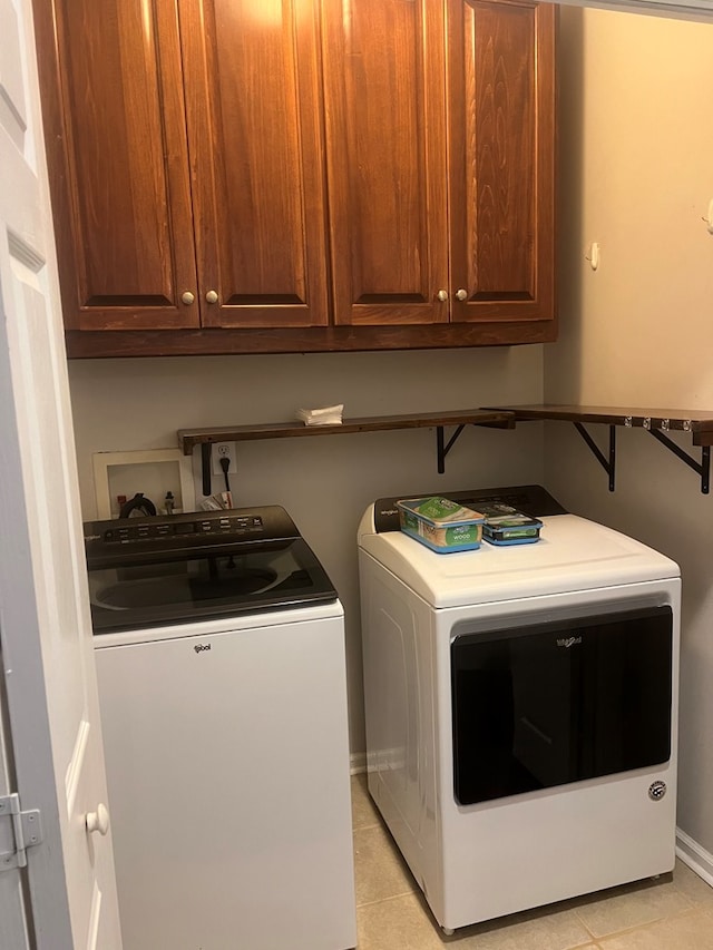 laundry room featuring washer and dryer, light tile patterned floors, and cabinets