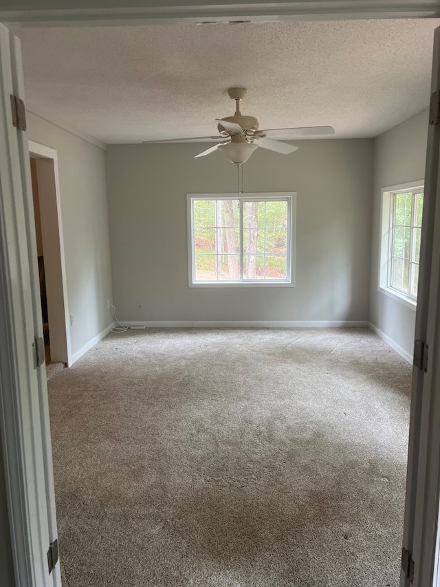 empty room featuring ceiling fan, a textured ceiling, and light carpet