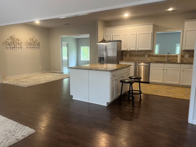 kitchen featuring dark stone counters, white cabinets, decorative backsplash, a kitchen island, and stainless steel appliances