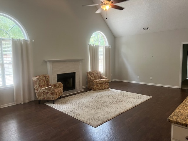 living room featuring a textured ceiling, vaulted ceiling, ceiling fan, a fireplace, and dark hardwood / wood-style floors