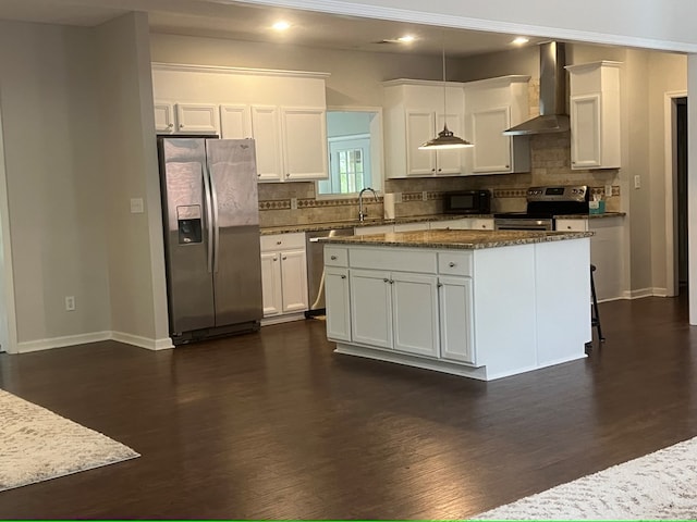 kitchen featuring wall chimney exhaust hood, white cabinetry, stainless steel appliances, and decorative light fixtures