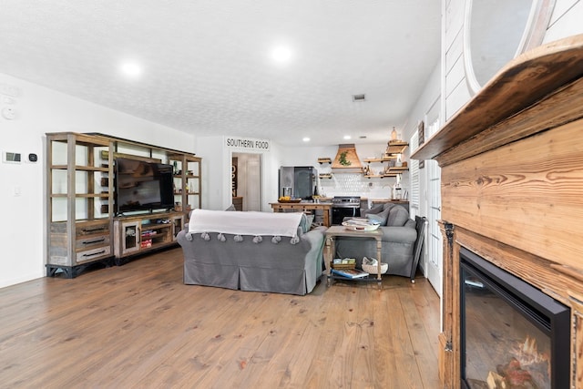111 Southlake Dr, Eatonton, GA 31024 - living room with a textured ceiling, a warm lit fireplace, wood-type flooring, visible vents, and recessed lighting