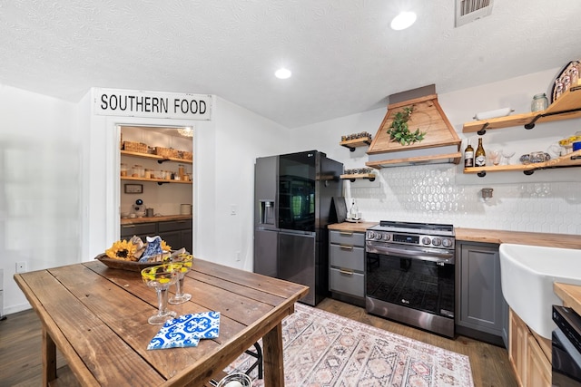 111 Southlake Dr, Eatonton, GA 31024 - kitchen with custom exhaust hood, black fridge with ice dispenser, open shelves, wooden counters, and electric stove