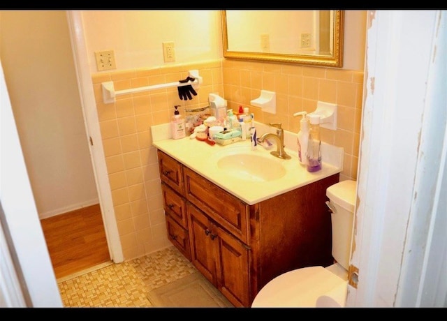 bathroom featuring tile patterned floors, vanity, tile walls, and toilet