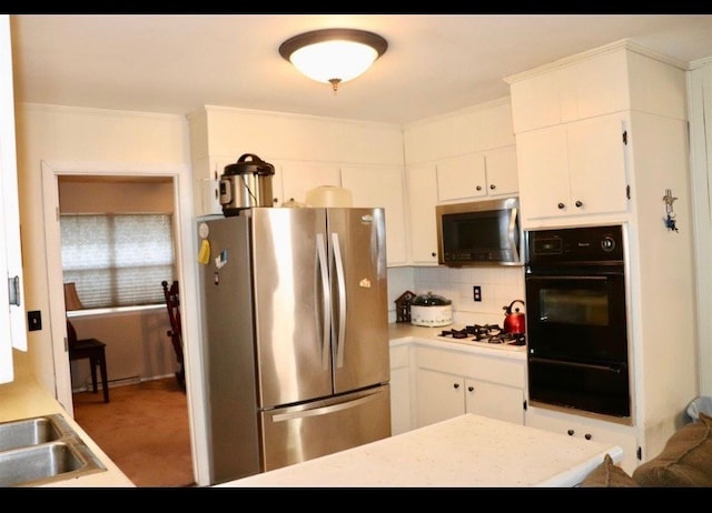 kitchen with decorative backsplash, white gas stovetop, sink, white cabinetry, and stainless steel refrigerator