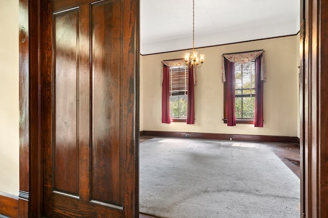 carpeted spare room featuring a notable chandelier