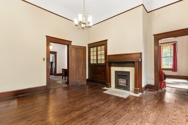 unfurnished living room featuring a towering ceiling, dark wood-type flooring, a tile fireplace, and an inviting chandelier