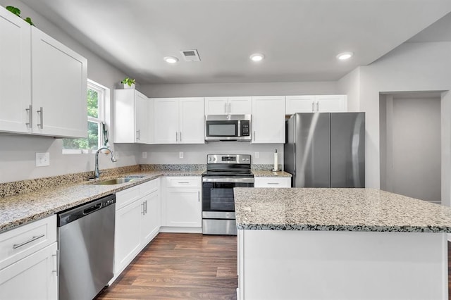 kitchen with dark hardwood / wood-style flooring, light stone counters, stainless steel appliances, sink, and white cabinetry