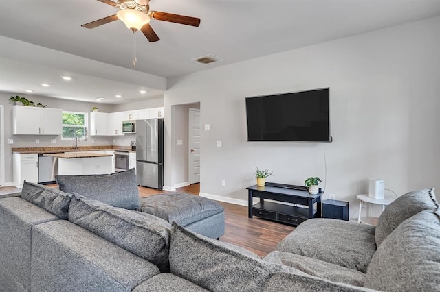 living room with ceiling fan, sink, and hardwood / wood-style flooring