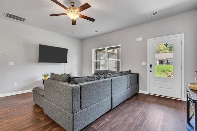 living room with a wealth of natural light, dark wood-type flooring, and ceiling fan